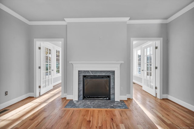 unfurnished living room featuring crown molding, plenty of natural light, and light wood-type flooring