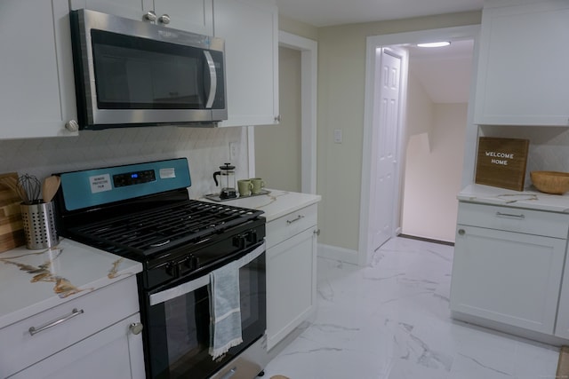 kitchen featuring white cabinets, stainless steel appliances, and light stone countertops