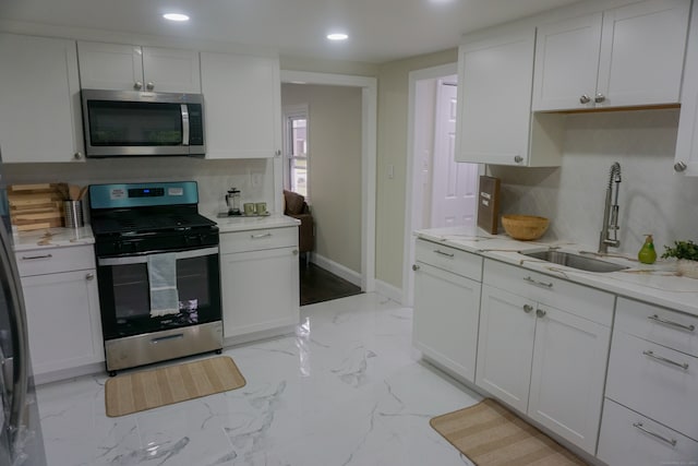 kitchen with white cabinets, appliances with stainless steel finishes, decorative backsplash, and sink