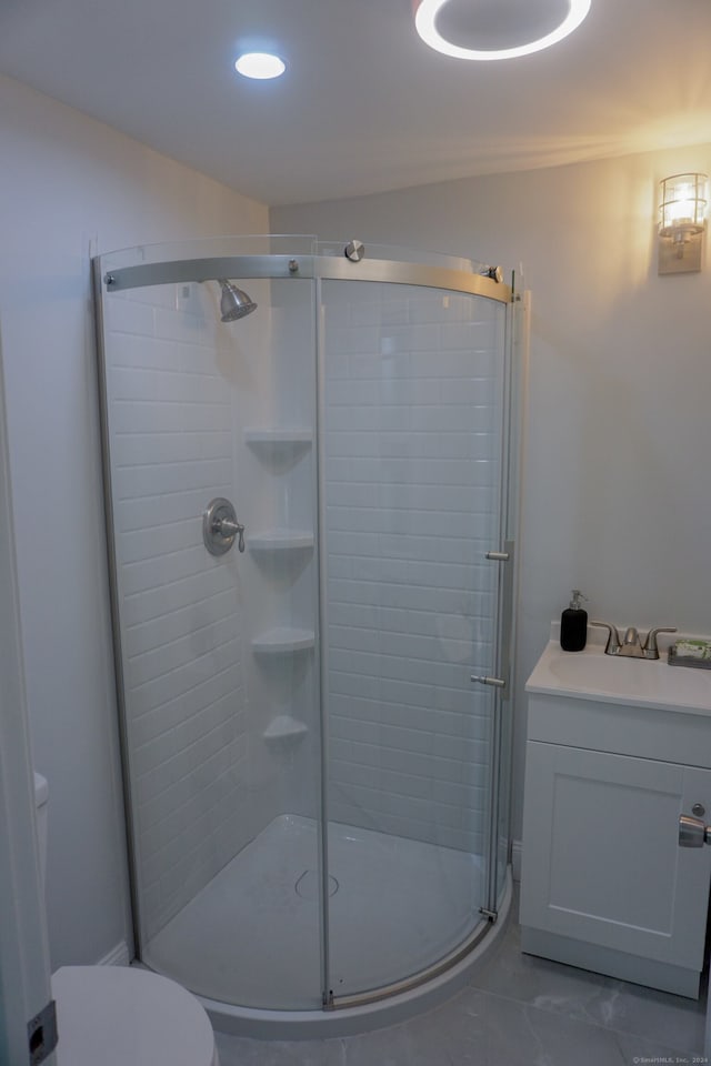 bathroom featuring toilet, a shower with shower door, and sink