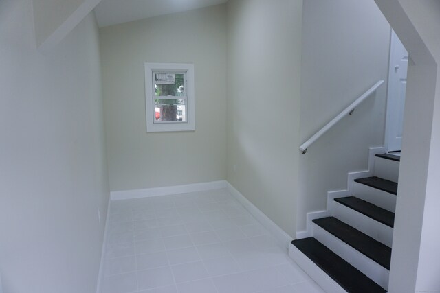 staircase featuring tile patterned floors and lofted ceiling