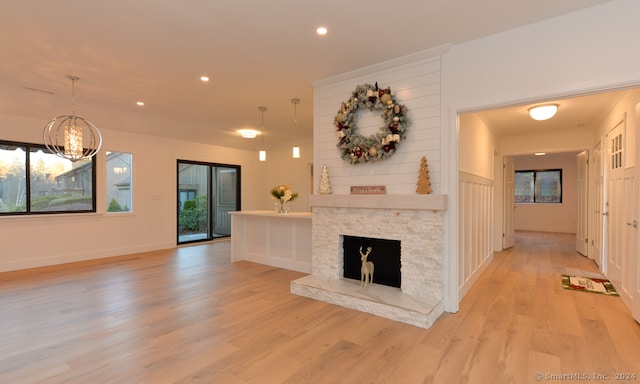 unfurnished living room with light wood-type flooring and a stone fireplace