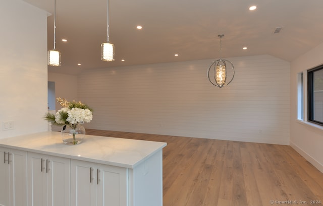 kitchen with white cabinets, pendant lighting, light wood-type flooring, and lofted ceiling