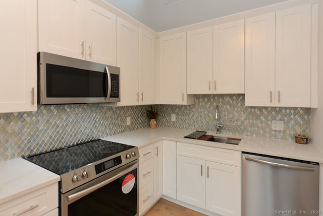 kitchen with decorative backsplash, appliances with stainless steel finishes, white cabinets, and sink