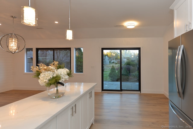 kitchen with white cabinetry, stainless steel fridge, hanging light fixtures, and light hardwood / wood-style floors