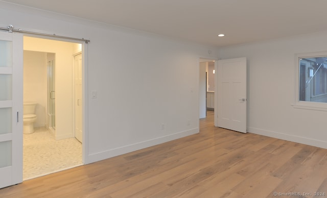 empty room with a barn door and light hardwood / wood-style flooring