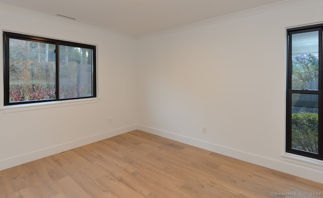 empty room featuring crown molding and light hardwood / wood-style flooring