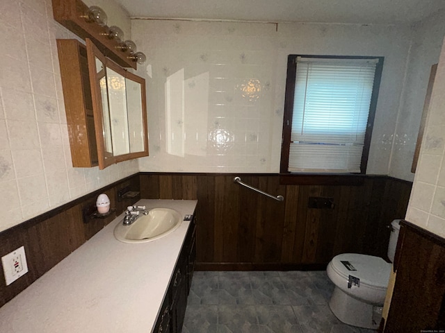 bathroom featuring vanity, wood walls, toilet, and tile walls