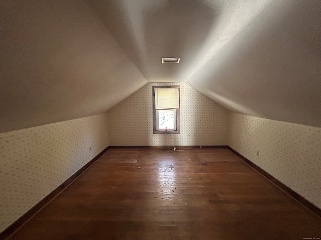 bonus room featuring dark wood-type flooring and vaulted ceiling