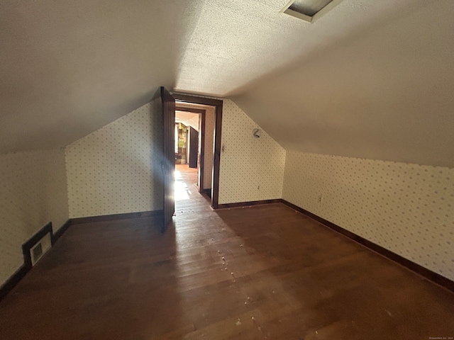 bonus room with a textured ceiling, dark wood-type flooring, and vaulted ceiling