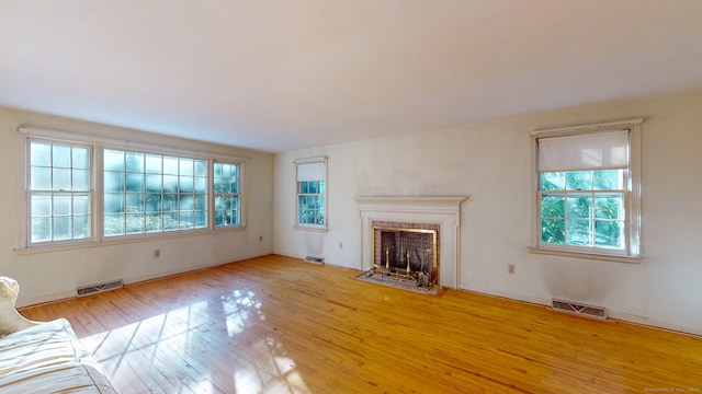 unfurnished living room featuring plenty of natural light and light hardwood / wood-style floors