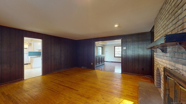 unfurnished living room featuring wood walls, a fireplace, and light hardwood / wood-style flooring