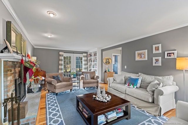 living room with a brick fireplace, light hardwood / wood-style flooring, french doors, and crown molding