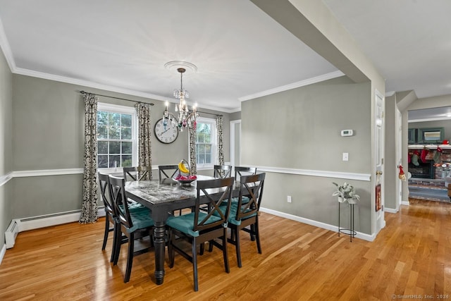 dining space with light wood-type flooring, crown molding, baseboard heating, and an inviting chandelier