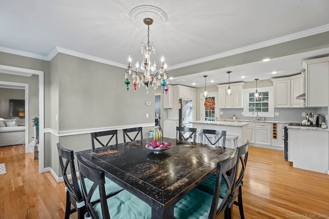 dining room featuring a notable chandelier, light hardwood / wood-style floors, ornamental molding, and sink