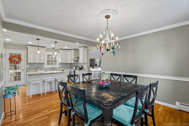 dining area with baseboard heating, light hardwood / wood-style flooring, ornamental molding, and an inviting chandelier