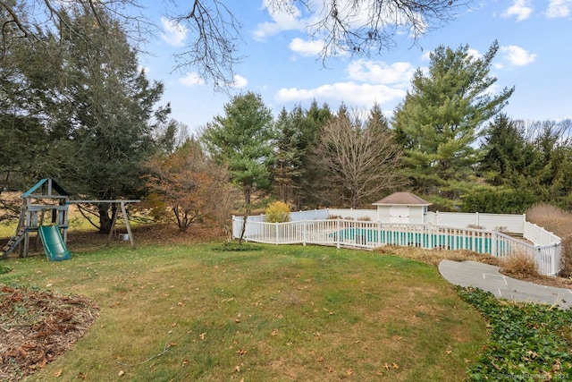 view of yard featuring a playground and a fenced in pool