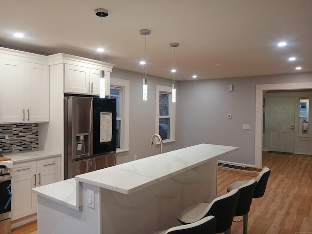 kitchen featuring white cabinets, stainless steel fridge, a center island, and tasteful backsplash