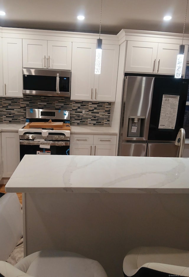 kitchen with decorative light fixtures, decorative backsplash, white cabinetry, and appliances with stainless steel finishes