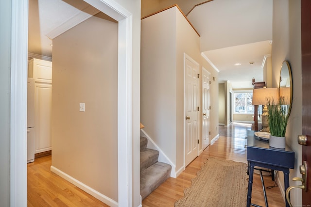 hallway with light hardwood / wood-style floors and crown molding