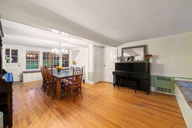 dining space featuring crown molding, wood-type flooring, and a notable chandelier