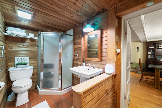 bathroom with sink, wooden ceiling, toilet, wooden walls, and a shower with door