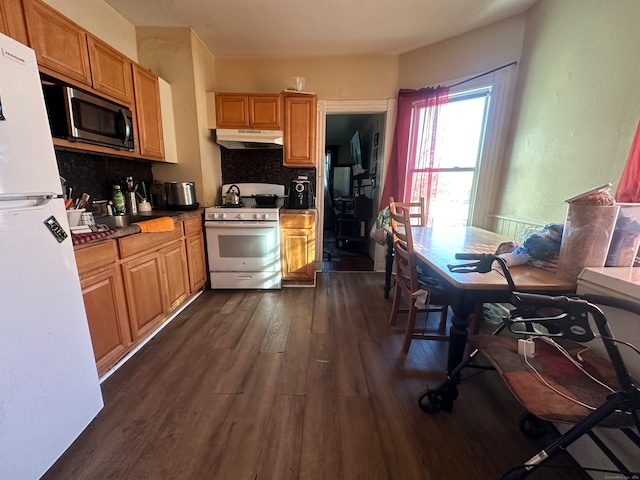 kitchen featuring white appliances, backsplash, and dark wood-type flooring