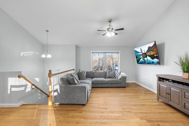 living room with high vaulted ceiling, light hardwood / wood-style floors, and ceiling fan with notable chandelier