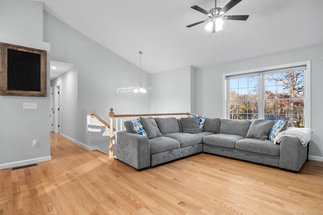 living room featuring light hardwood / wood-style flooring, high vaulted ceiling, and ceiling fan with notable chandelier