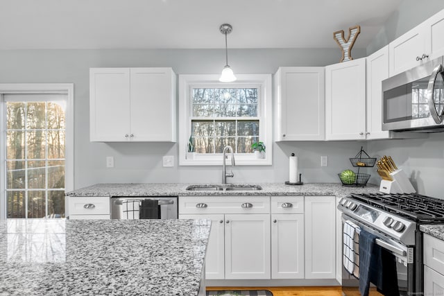 kitchen with light stone counters, sink, white cabinets, and stainless steel appliances