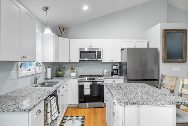 kitchen featuring appliances with stainless steel finishes, a breakfast bar, vaulted ceiling, sink, and hanging light fixtures