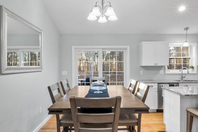 dining space featuring light wood-type flooring, an inviting chandelier, a wealth of natural light, and sink