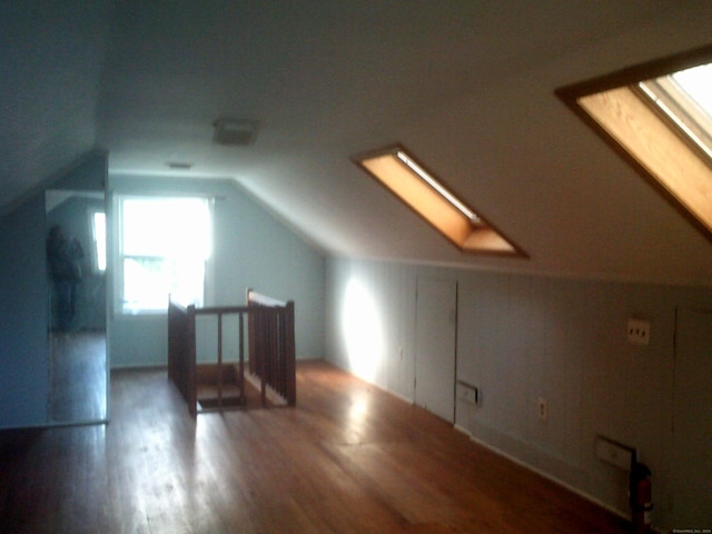 additional living space with dark hardwood / wood-style flooring and vaulted ceiling with skylight