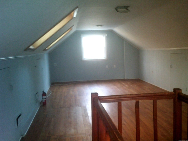 bonus room with lofted ceiling with skylight and dark wood-type flooring