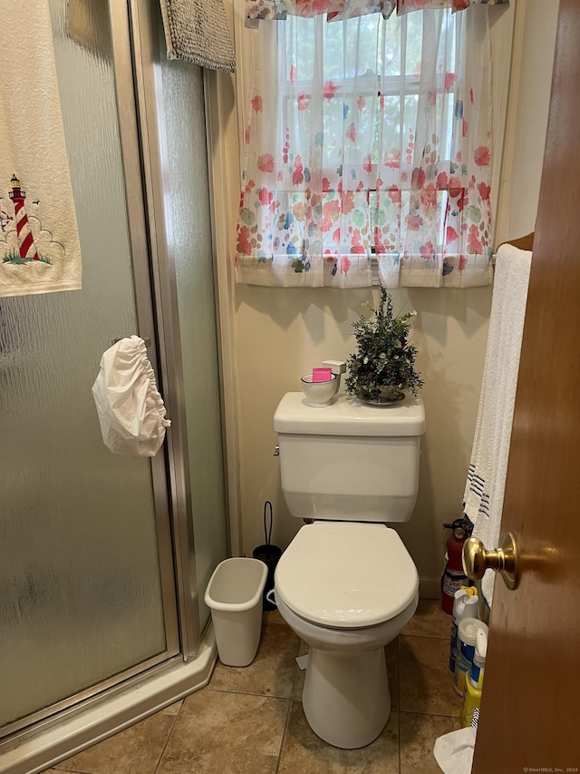 bathroom featuring tile patterned floors, a shower with shower door, and toilet