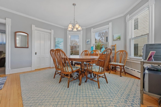 dining area with a chandelier, ornamental molding, light hardwood / wood-style flooring, and a baseboard heating unit