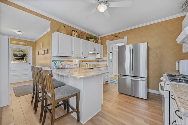 kitchen featuring light stone counters, crown molding, white appliances, a kitchen bar, and white cabinets