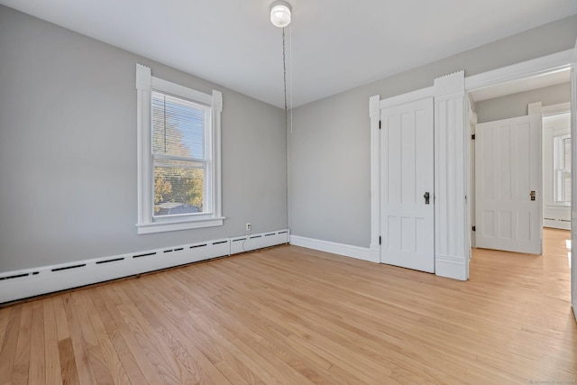 empty room featuring baseboard heating and light hardwood / wood-style flooring