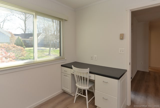 unfurnished office featuring hardwood / wood-style flooring, built in desk, and ornamental molding