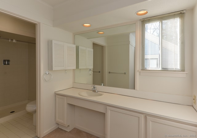 bathroom featuring tile patterned flooring, a tile shower, vanity, and toilet