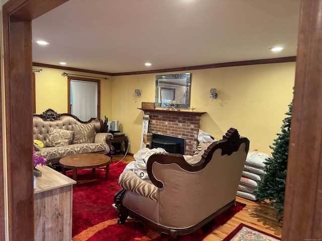 living room with hardwood / wood-style floors, a brick fireplace, and ornamental molding