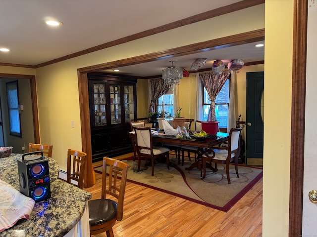 dining area featuring a chandelier, light hardwood / wood-style floors, and crown molding