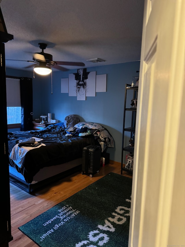 bedroom featuring ceiling fan, wood-type flooring, and a textured ceiling