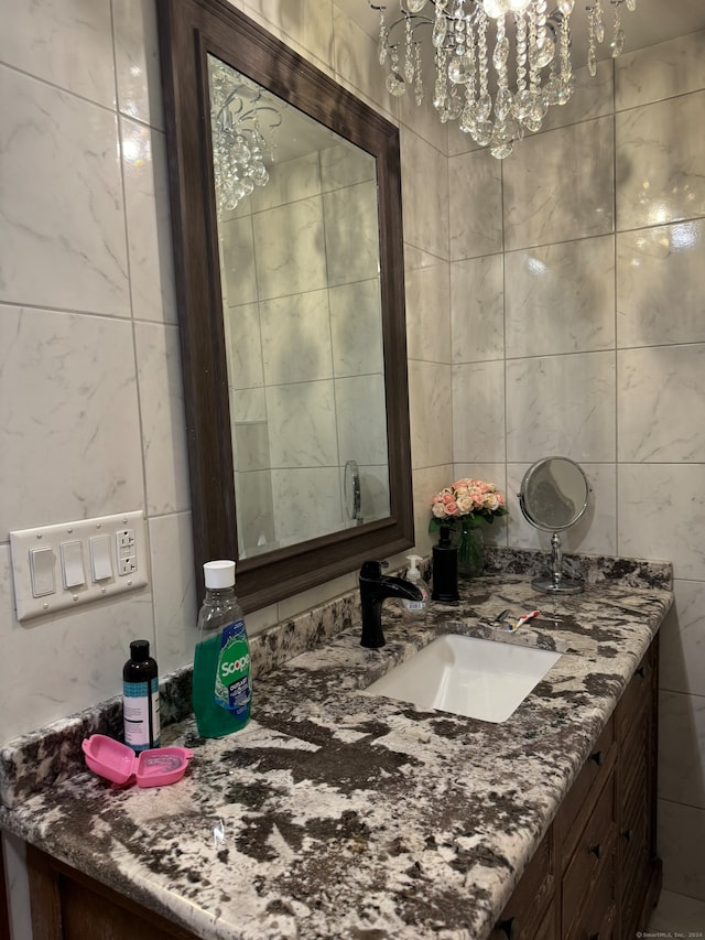 bathroom with a chandelier, vanity, and tile walls