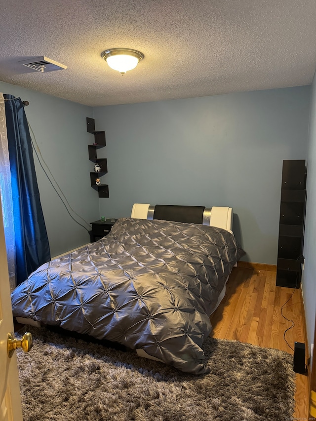 bedroom featuring hardwood / wood-style floors and a textured ceiling