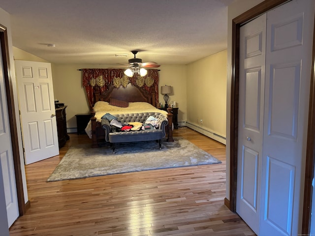 bedroom with a textured ceiling, ceiling fan, a baseboard radiator, light hardwood / wood-style floors, and a closet