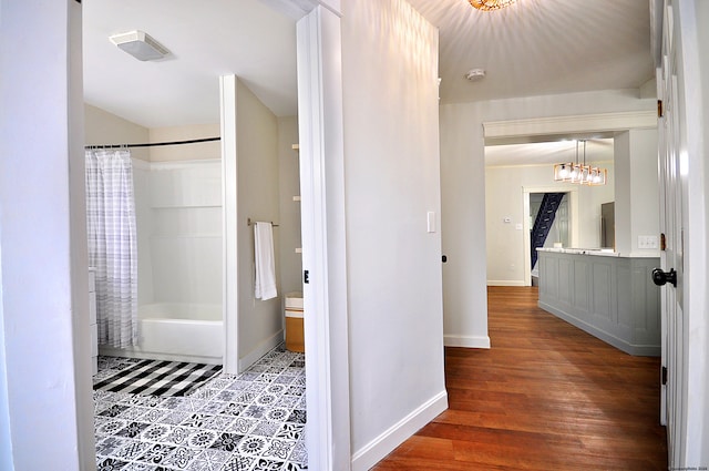 bathroom featuring a chandelier, wood-type flooring, and shower / bath combo with shower curtain