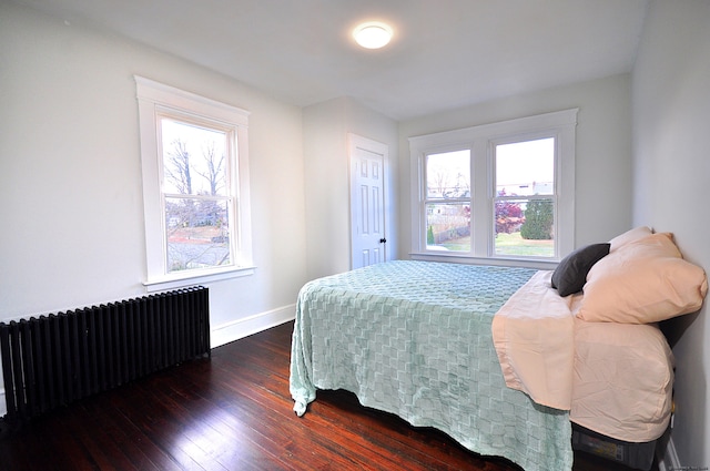 bedroom with dark hardwood / wood-style floors and radiator