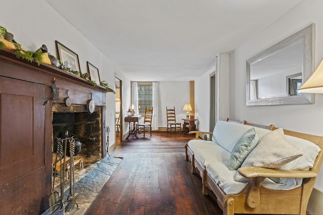 living room with dark hardwood / wood-style floors and a stone fireplace