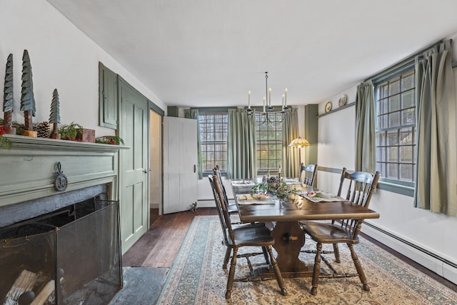 dining area featuring dark hardwood / wood-style floors, a baseboard heating unit, and a notable chandelier